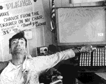 Photo: George, using an antique electric aug. comm. device with a light-up display
