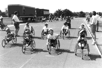 Photo: Children on three-wheeled racing wheelchairs on a track