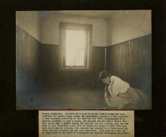woman holds head in hands seated in a room in an asylum