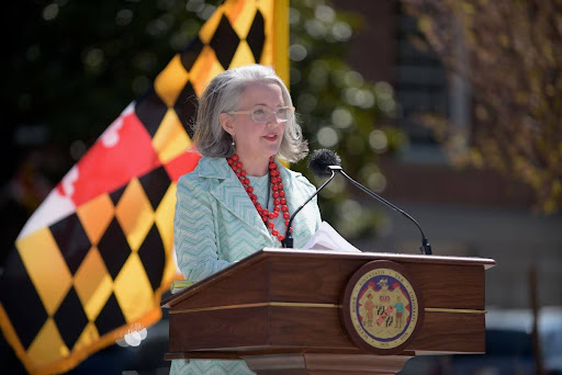 Photograph of Elaine Rice Bachmann speaking at a lectern with the Maryland state flag behind her.